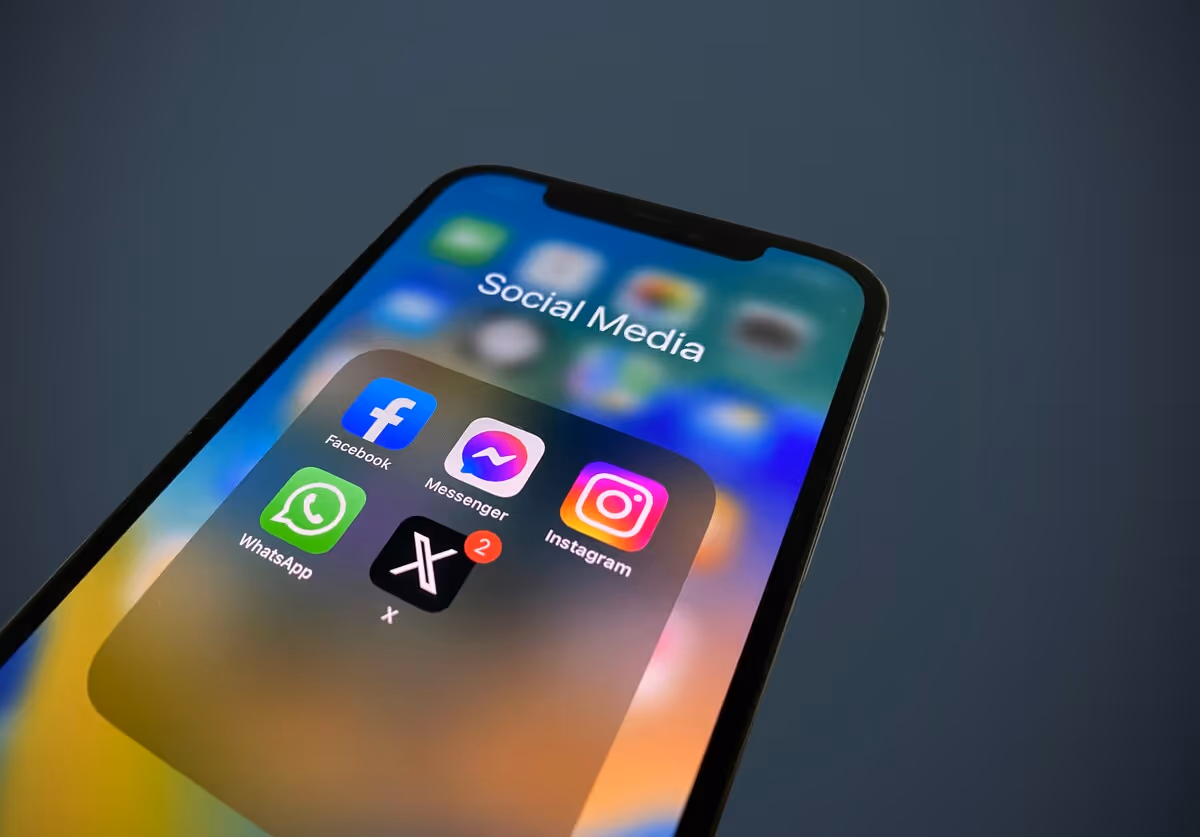 Smartphone screen displaying a folder labeled Social Media with Facebook, Messenger, Instagram, WhatsApp, and X apps.