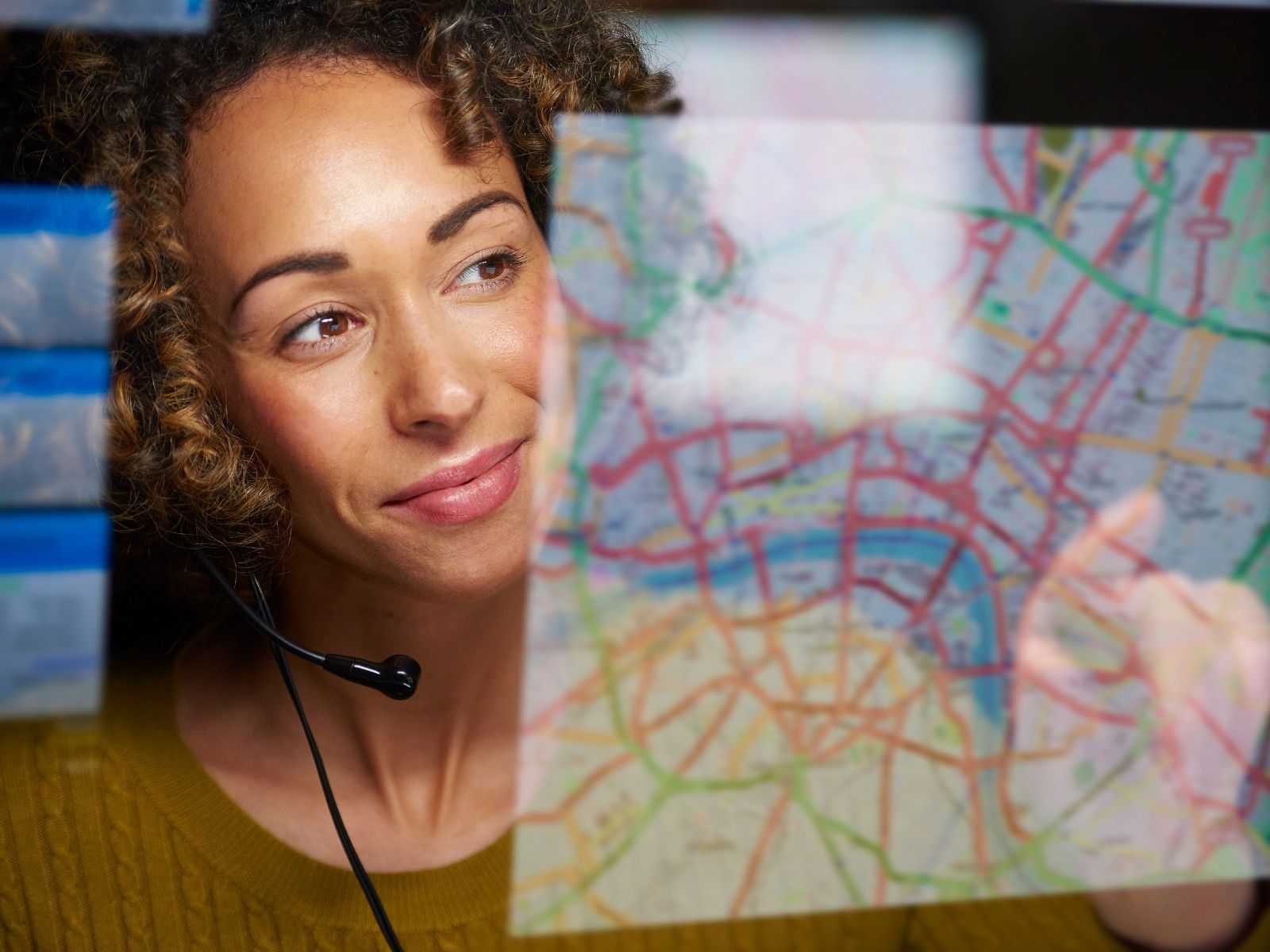 Woman wearing headset looking at a transparent map with various colored routes.