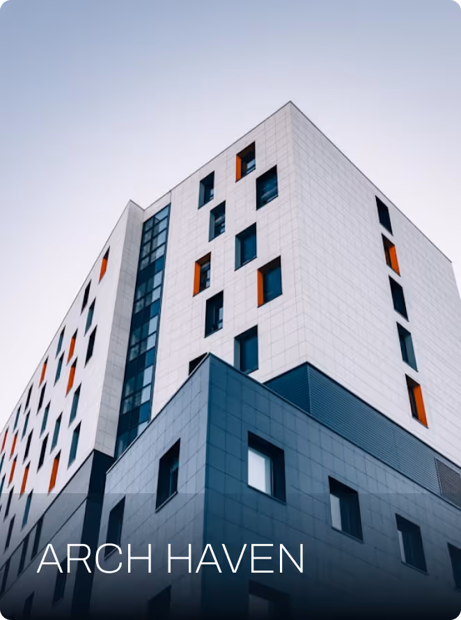 Modern multi-story building with white and gray sections featuring small square windows and orange accents.