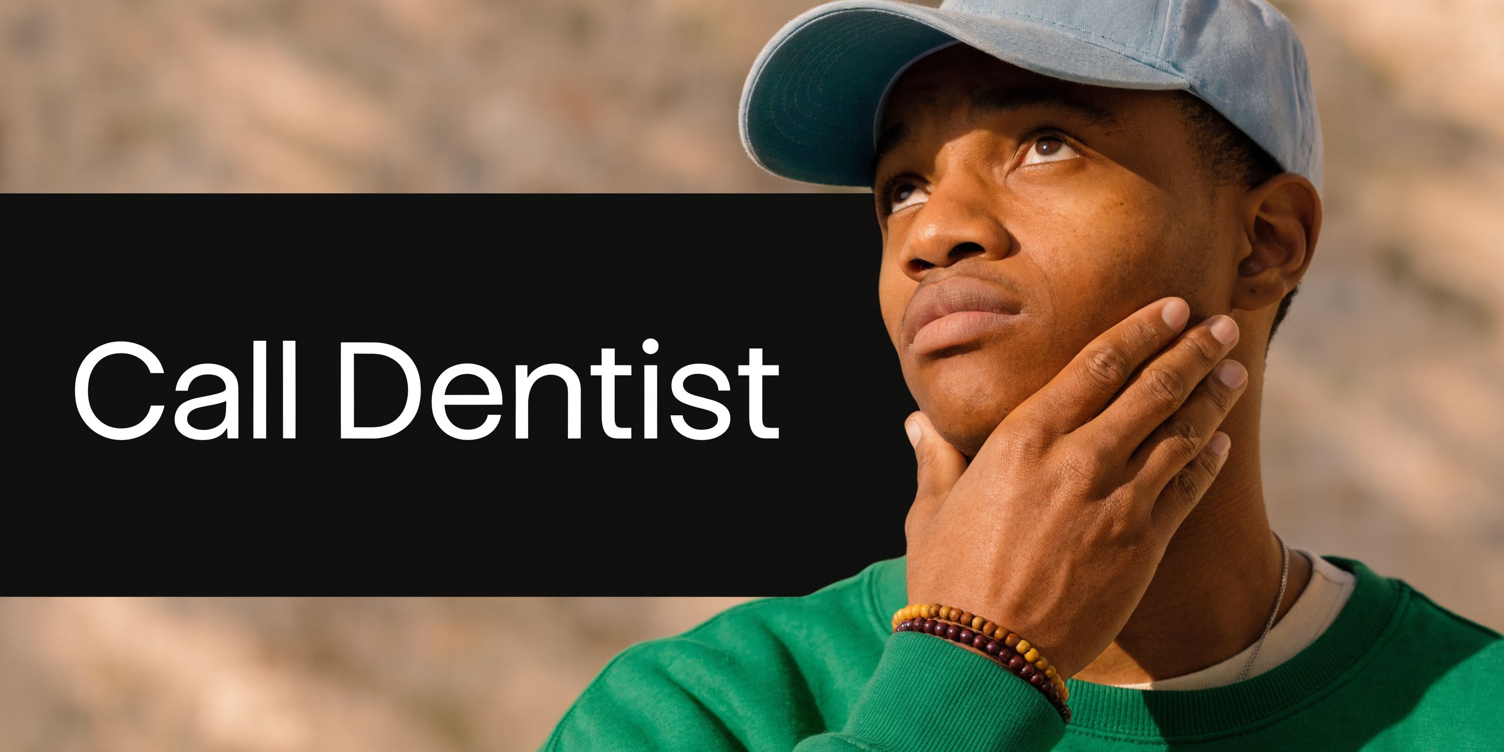 A young man wearing a cap touching his jaw while looking up, illustrating tooth pain or sensitivity.
