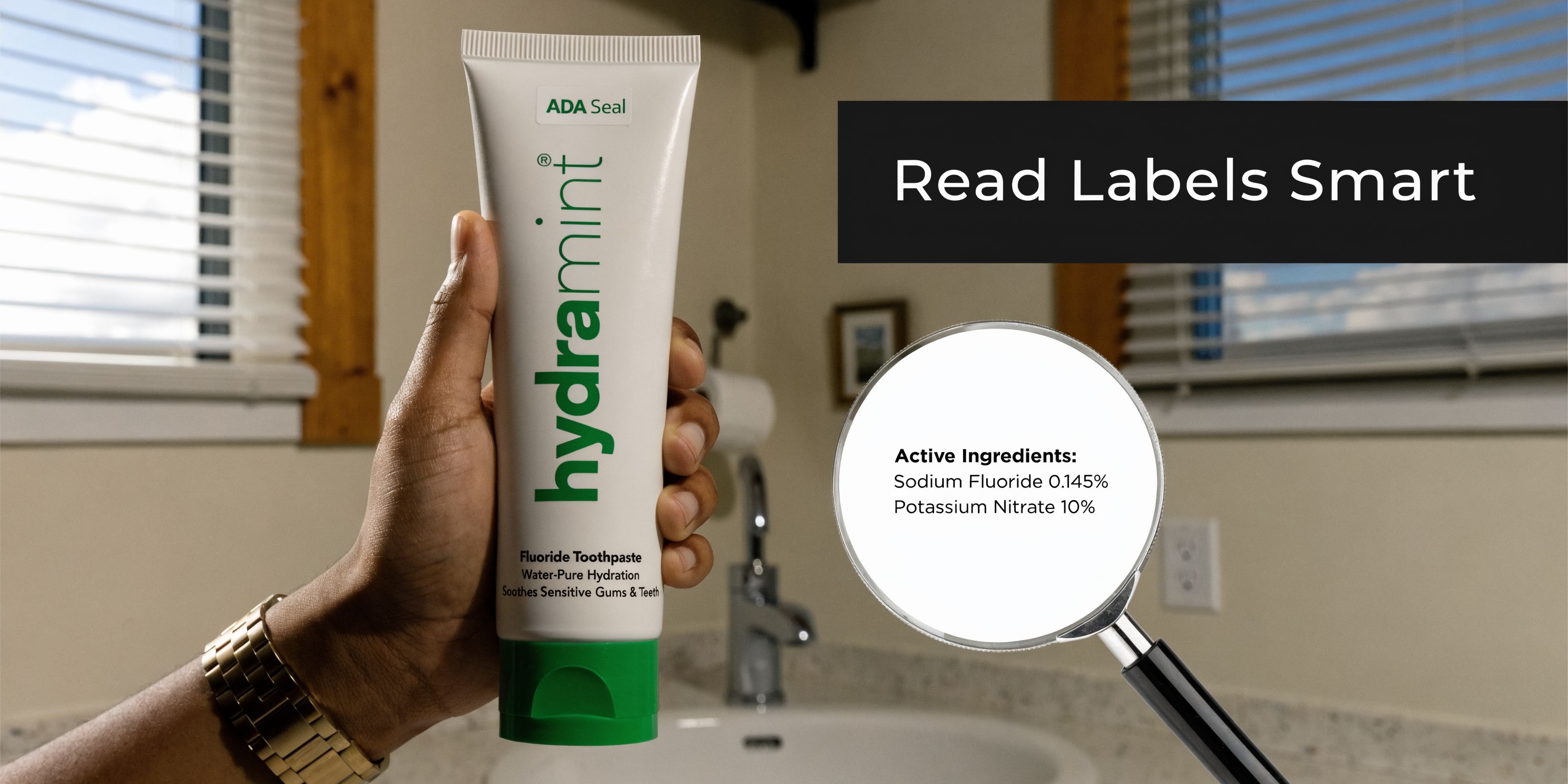 A hand holding a tube of Hydramint toothpaste with a magnifying glass showing active ingredients list.