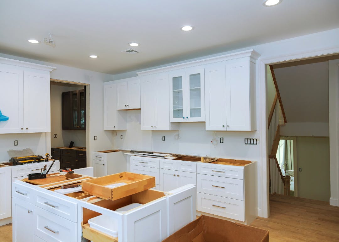 Kitchen under renovation with white cabinets being installed and drawers unfinished.