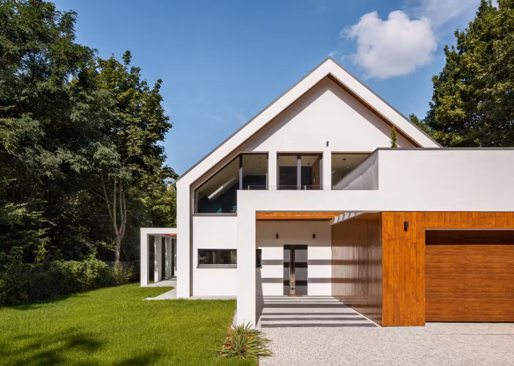 Modern two-story house with white walls, large windows, and wood accents.