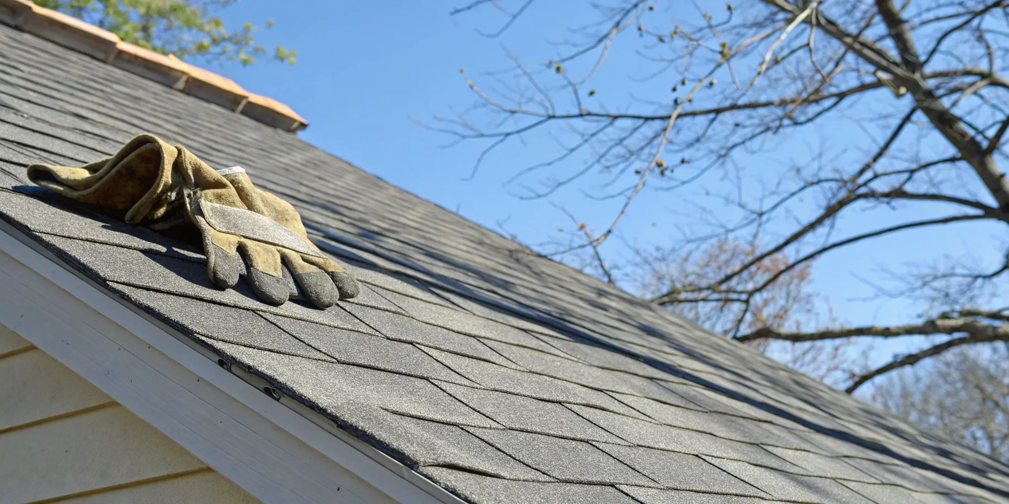 Work gloves on new asphalt shingles, factoring into the average cost to replace a roof.
