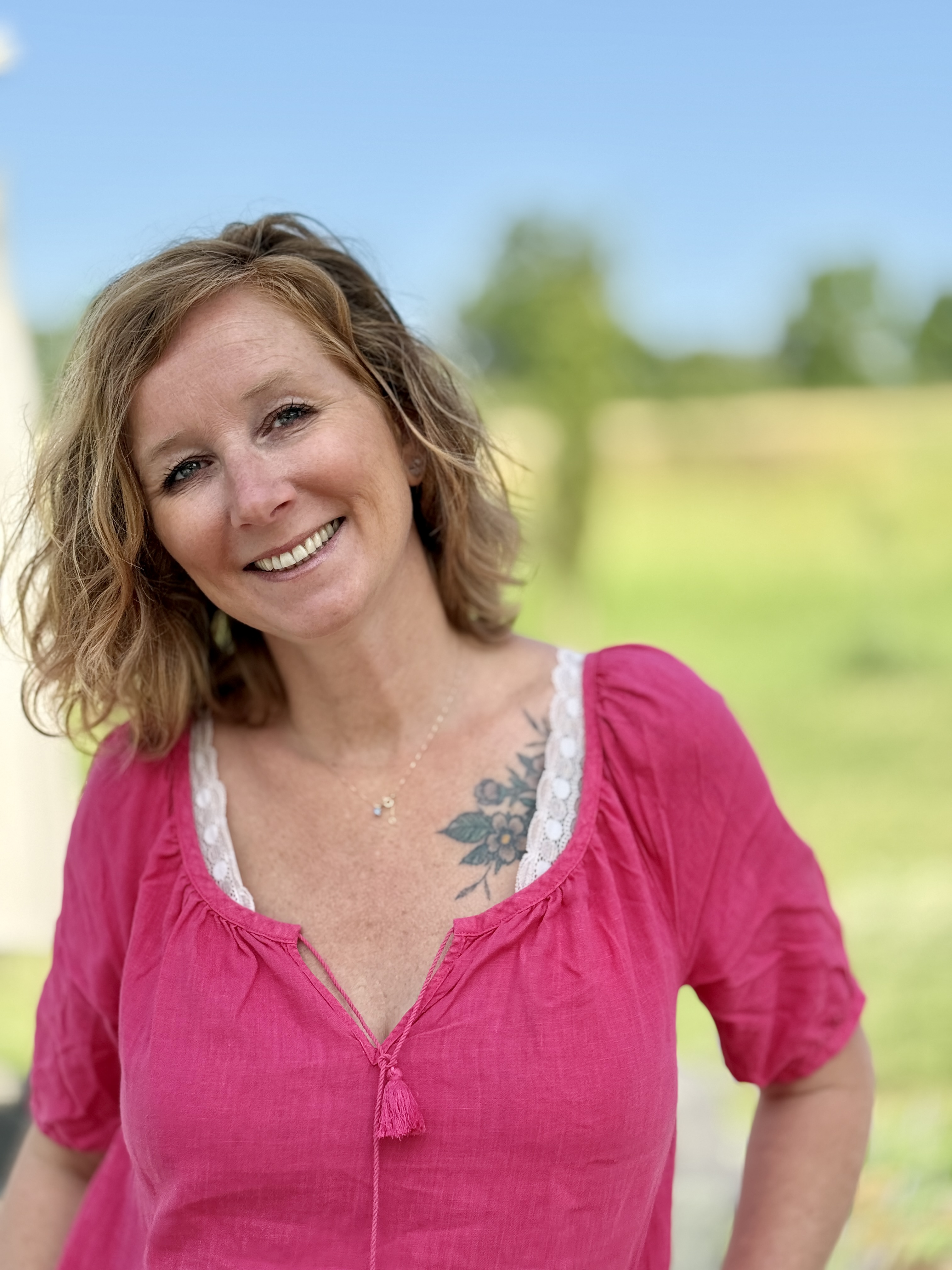 jeune femme avec un grand sourire, dans la nature, avec une robe rose