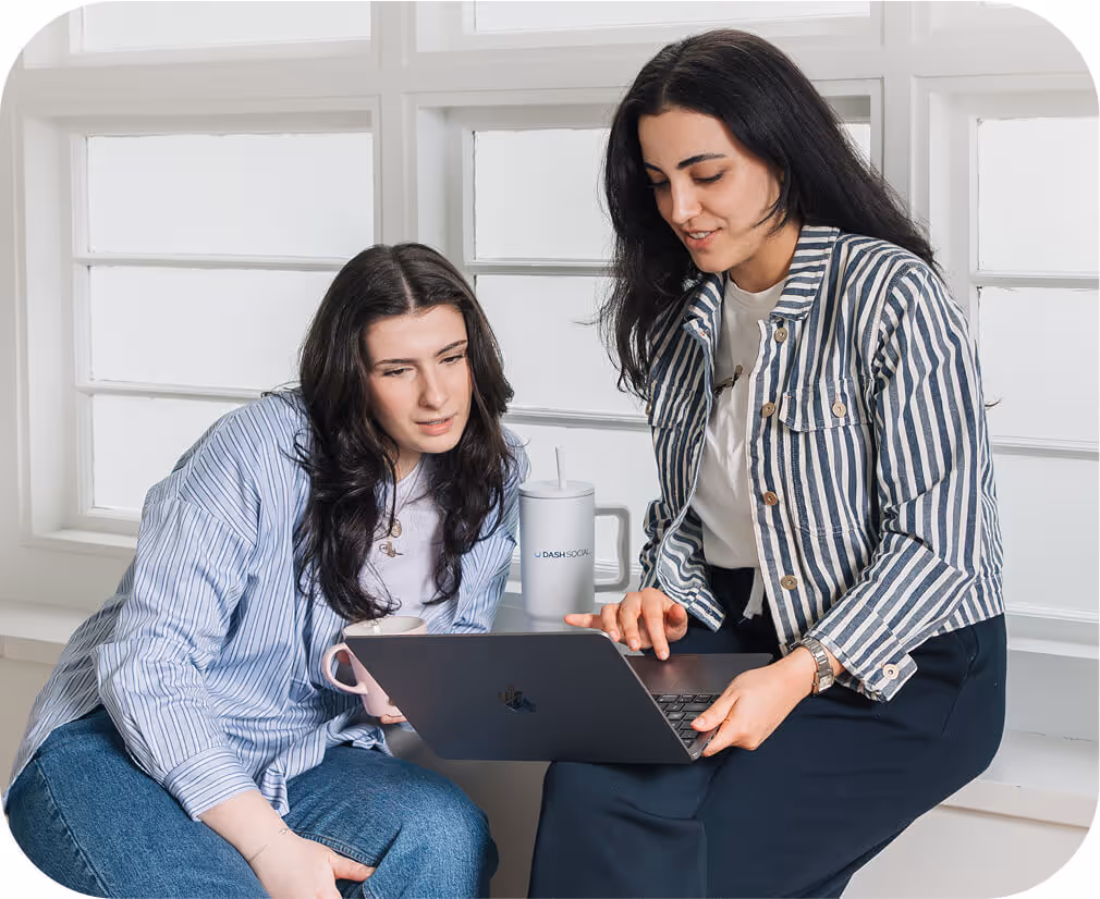 Two women collaborating on laptop with Dash Social tumbler
