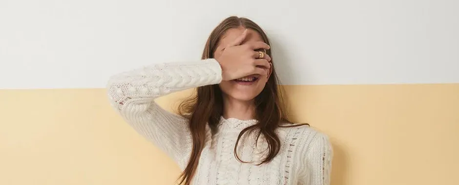 girl smiling covering her eyes