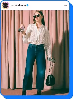 woman posing in front of pink curtain wearing mother jeans 