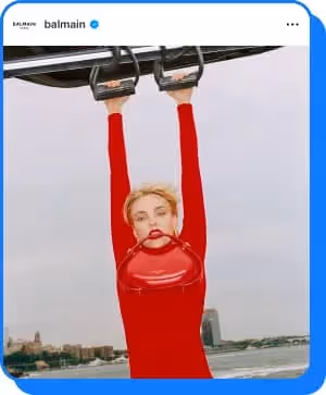 woman wearing red turtleneck holding purse in teeth for balmain