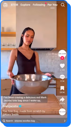 a woman in a black dress holding a large metal mixing bowl in a minimalist kitchen