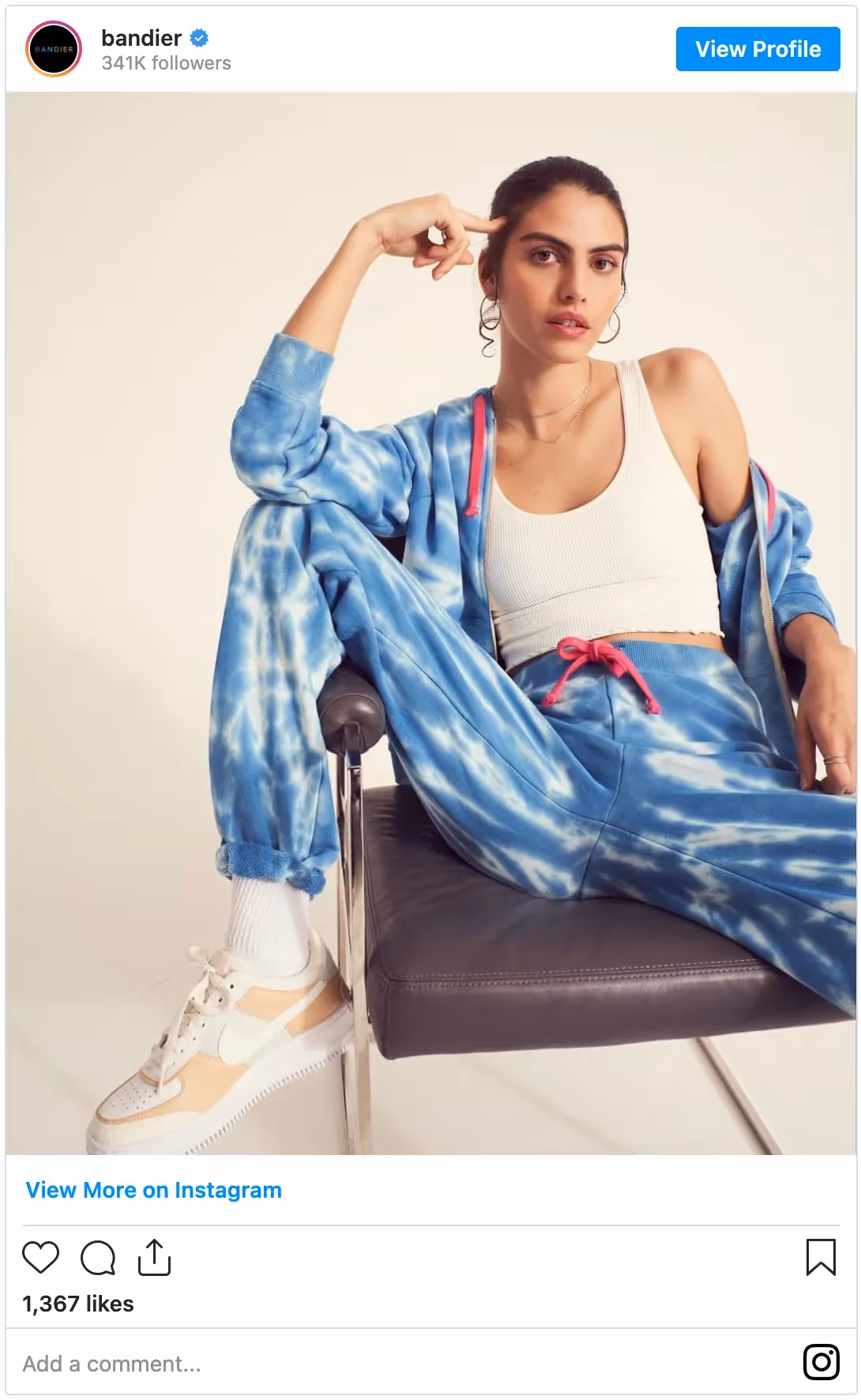 Bandier model on a chair wearing blue tie dye track suit