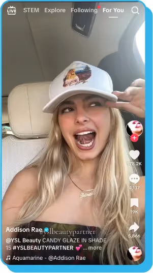 TikTok video of a creator in a car, wearing a white cap and laughing while promoting beauty products.