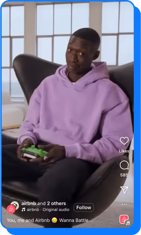 man in a purple hoodie holding a game controller while sitting in a modern black chair.