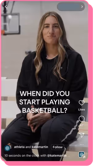 Woman in black tracksuit sits on bench in gym with basketball hoop in background