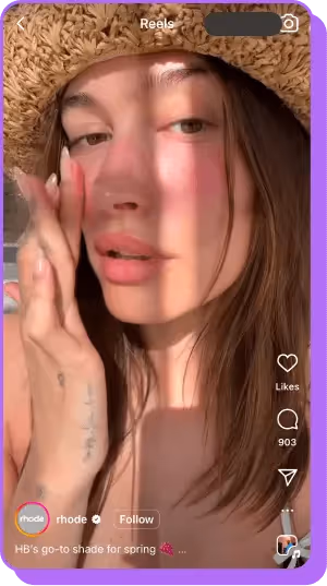 Woman in sun hat applying blush in beauty brand Instagram reel.