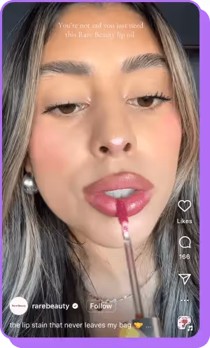 Woman applying Rare Beauty lip oil with text overlay promoting the product