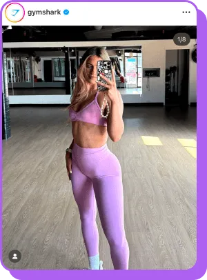 Woman taking mirror selfie in pink Gymshark set in workout studio
