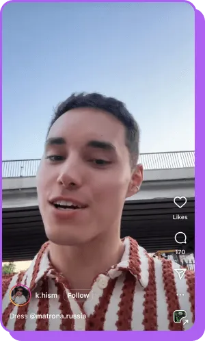 Man in a red and white striped shirt speaking outdoors near an overpass.