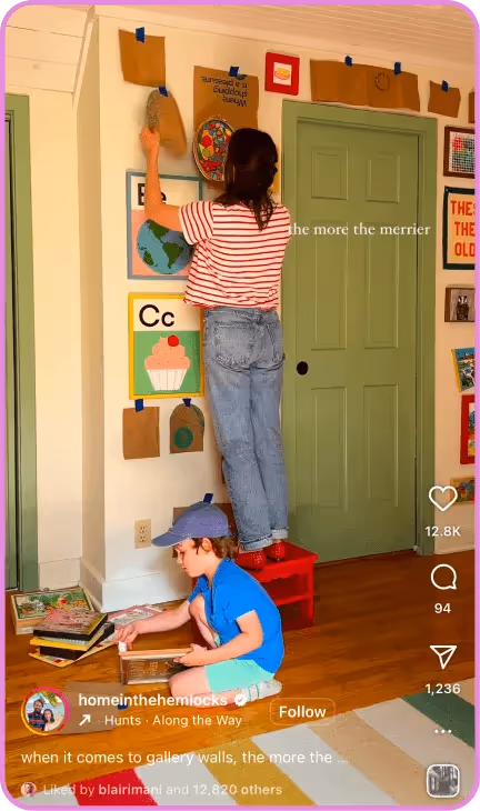 Woman decorating wall while child reads books on floor
