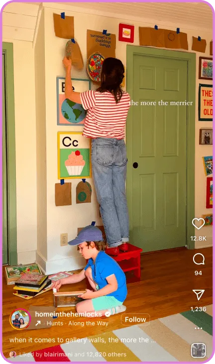 Woman decorating wall while child reads books on floor