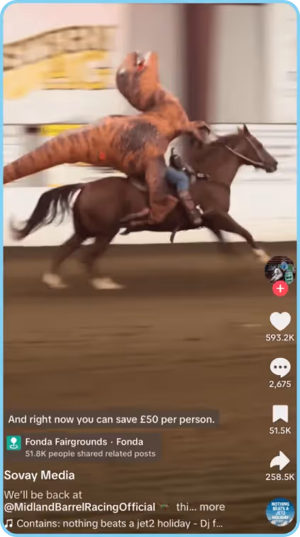 Person in inflatable dinosaur costume riding a galloping horse in an arena.