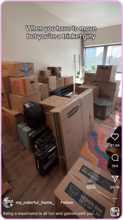 Stacked moving boxes fill a brightly lit room with caption about being a trinket collector.