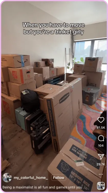 Stacked moving boxes fill a brightly lit room with caption about being a trinket collector.
