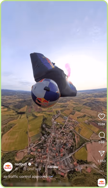 Instagram video still of Red Bull wingsuit flyer soaring above landscape.