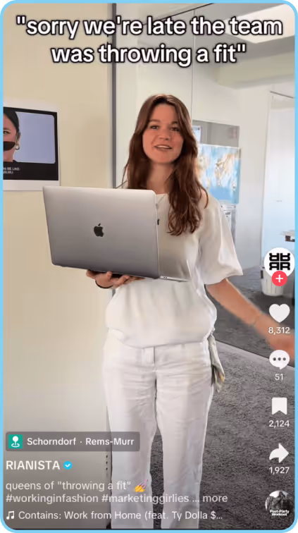 Woman in white outfit holding laptop, joking about team issues in office setting.