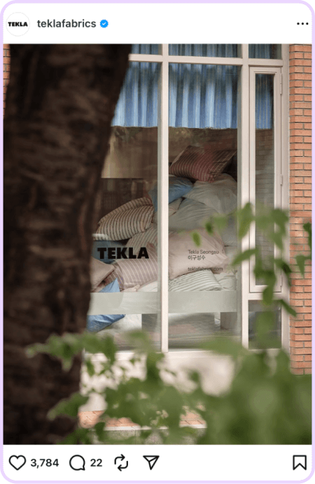 Window view of Tekla bedding display with striped pillows and duvets stacked indoors