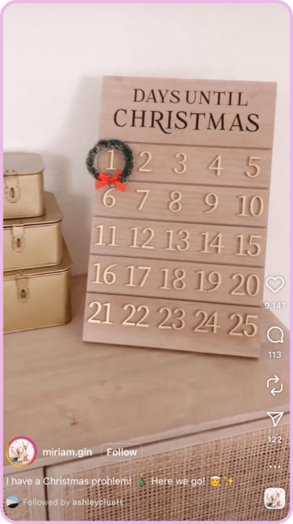 Wooden countdown calendar with wreath marks days until Christmas, styled on neutral dresser.