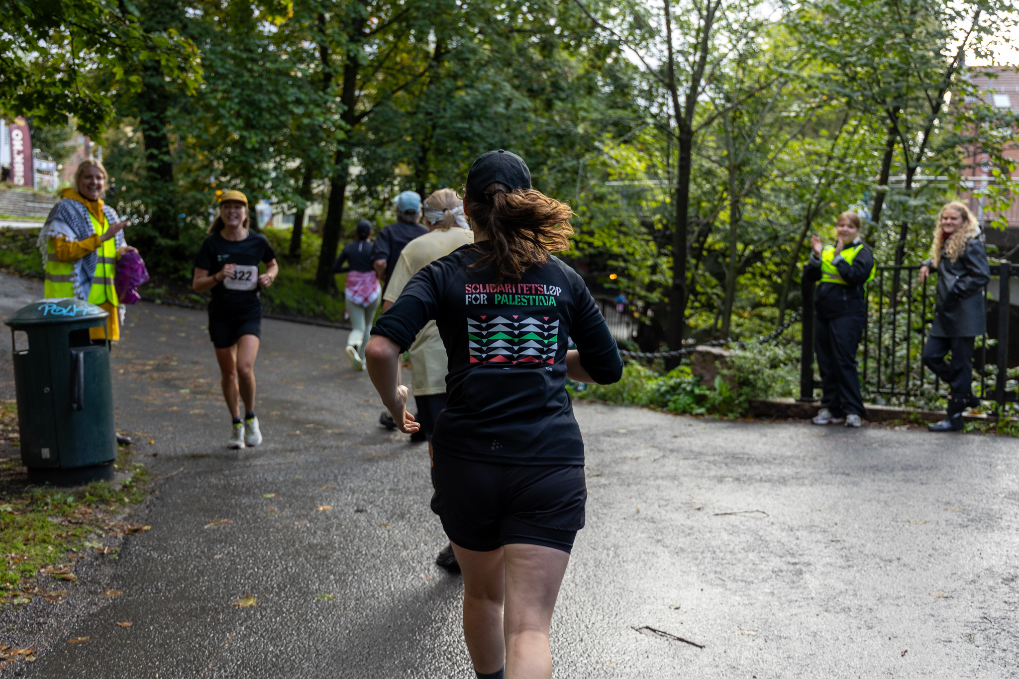 En jogger sett bakfra løper med t-skjorte fra Solidaritetsløp for Palestina. Motgående løper på siden.