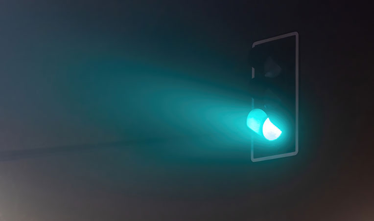 Image of green traffic light surrounded by fog at night
