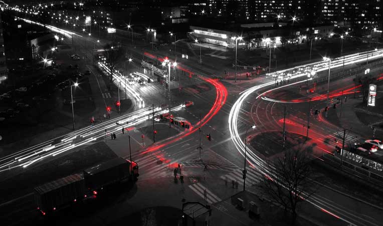 Drone of an intersection at night with vehicles travelling quickly