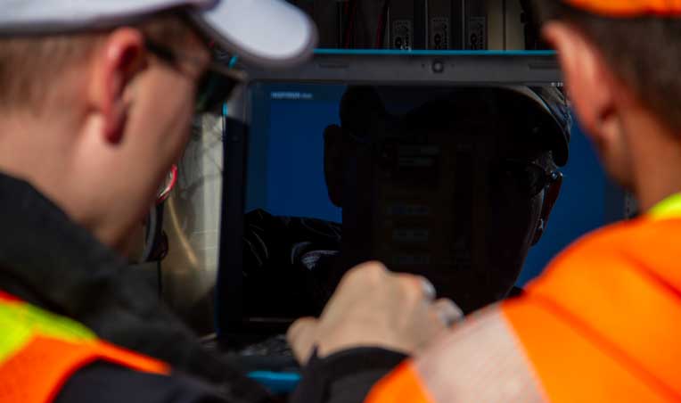 Techs working on laptop in traffic cabinet