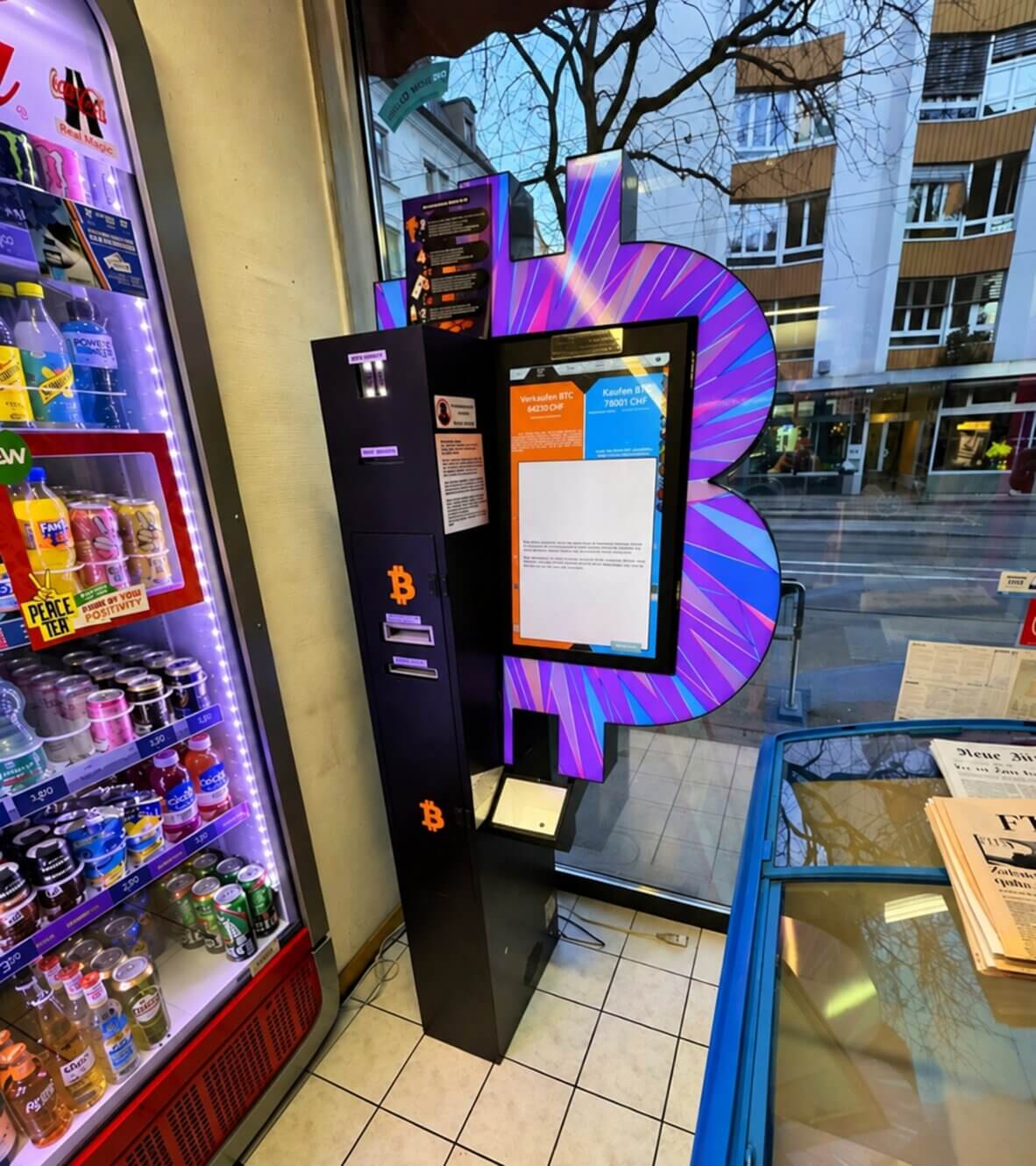 Wnętrze sklepu z Bitcoin ATM ustawionym między wejściem a strefą kas