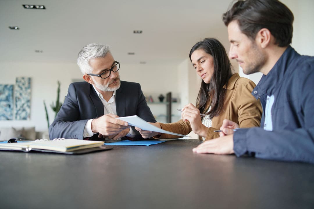 Homeowners reviewing a foundation repair estimate with a consultant at a desk