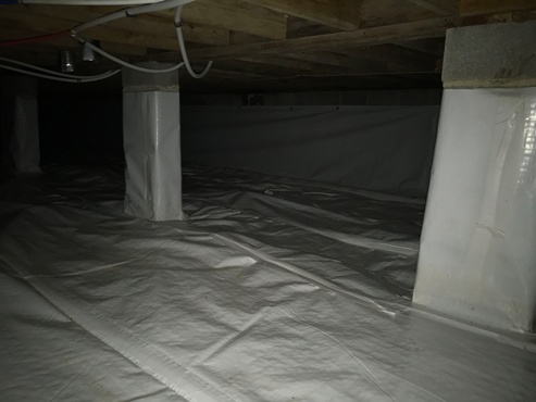 Encapsulated crawl space with white vapor barrier floor, wrapped support piers and sealed walls for moisture control