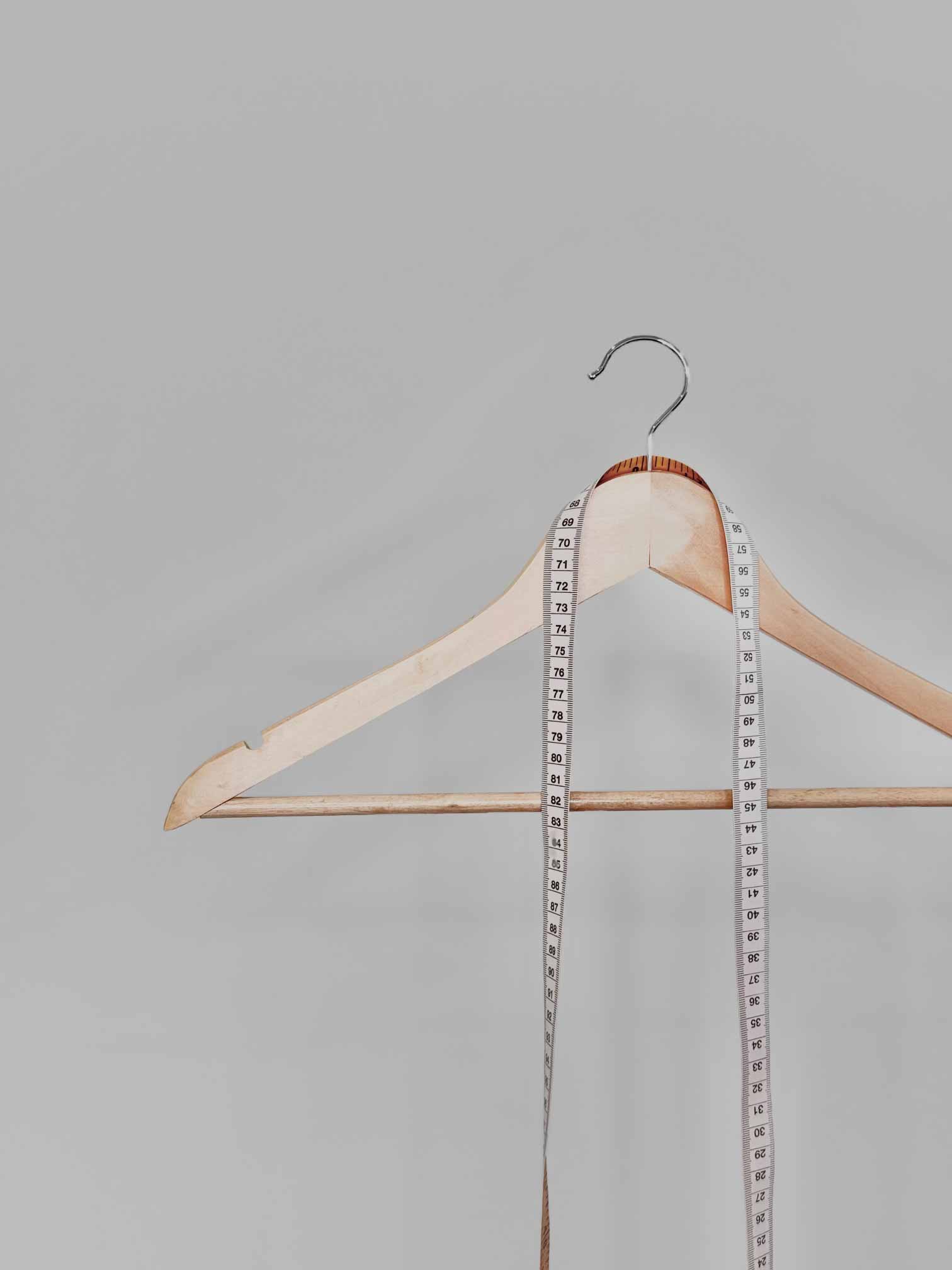 Wooden hanger with tape measure draped around neck
