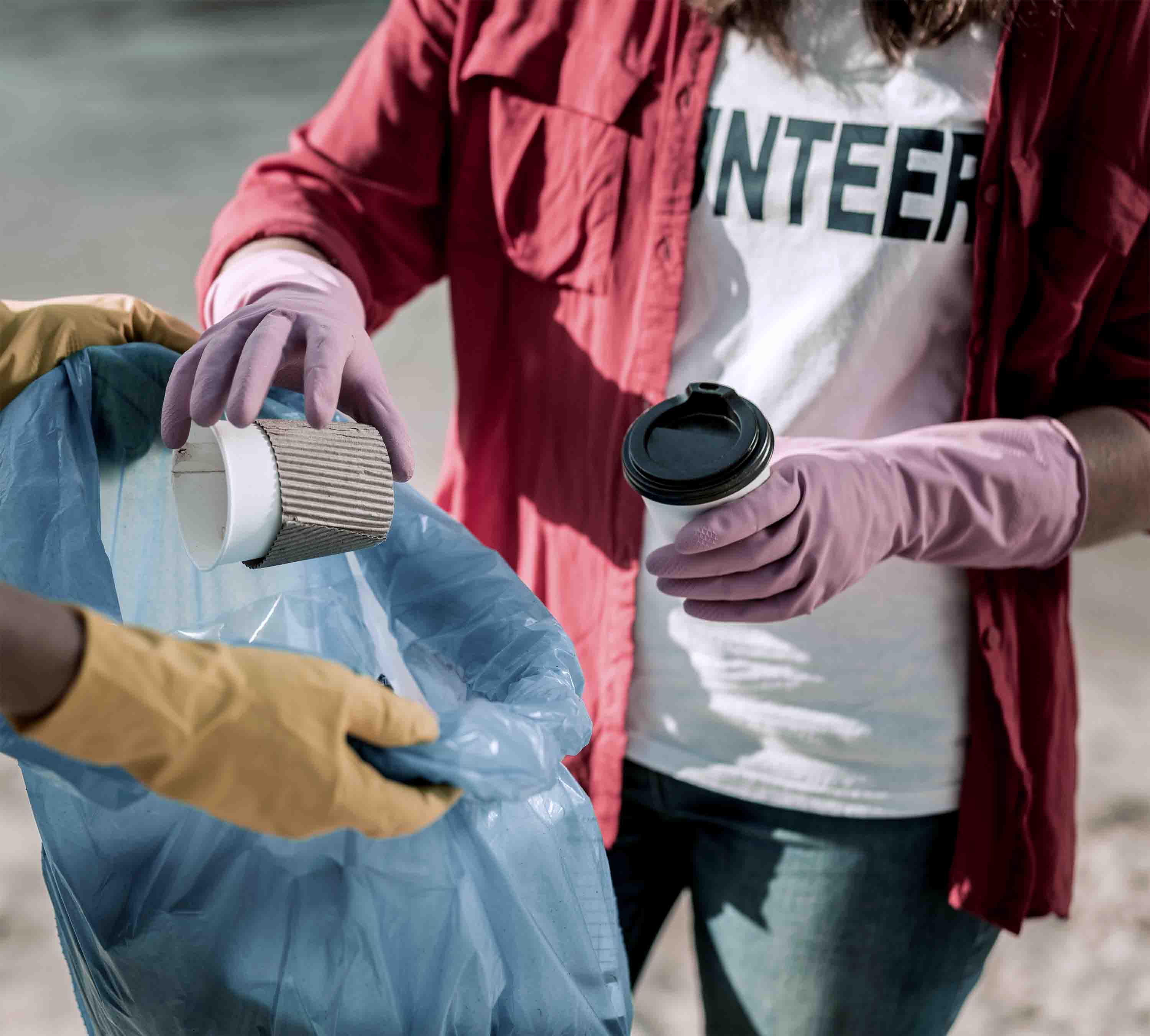 A close-up of a volunteer placing trash into a garbage bag.