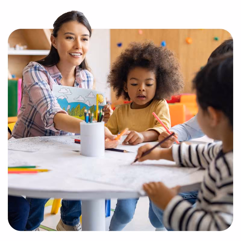 Adult and children engaging in activities at a table with paper and crayons.