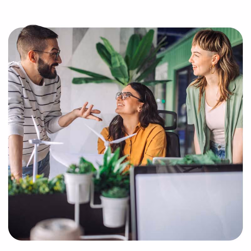 Three individuals in a modern office space with plant decor.