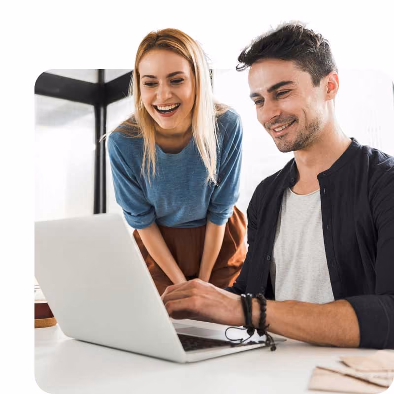 Two people working together on a laptop in a bright office setting.