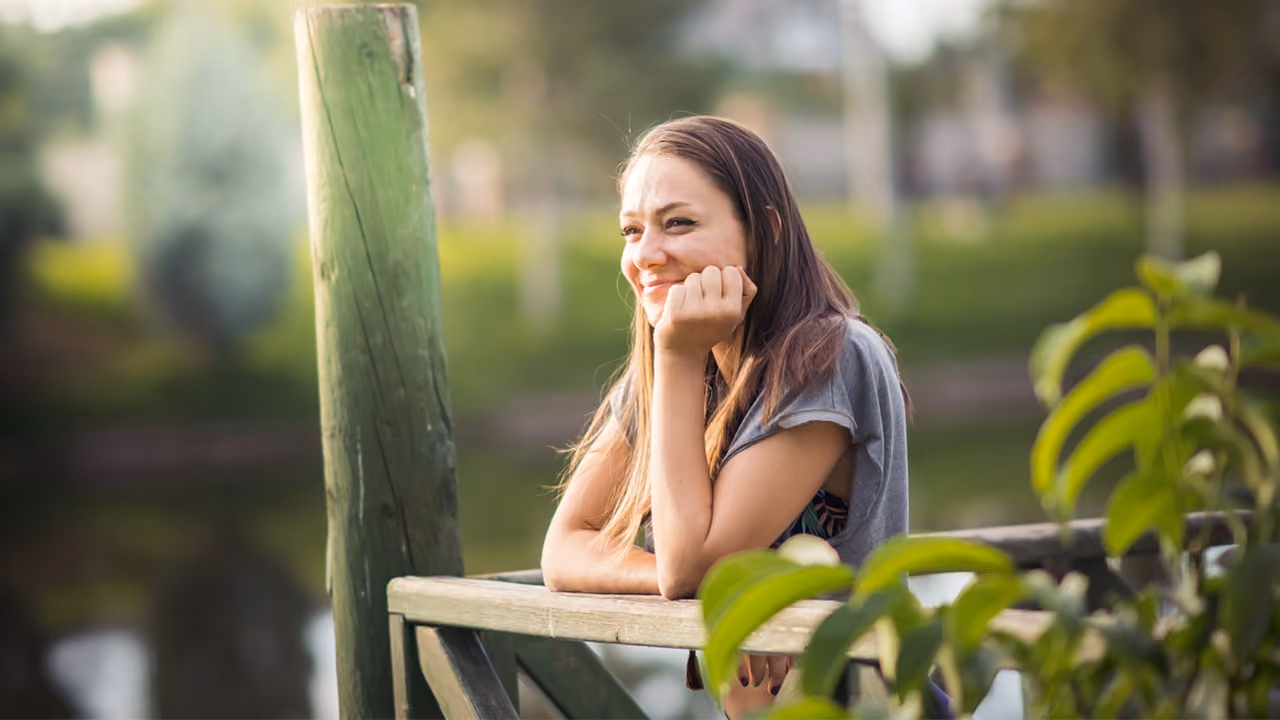 A young girl, leaning on bench looking relaxed
