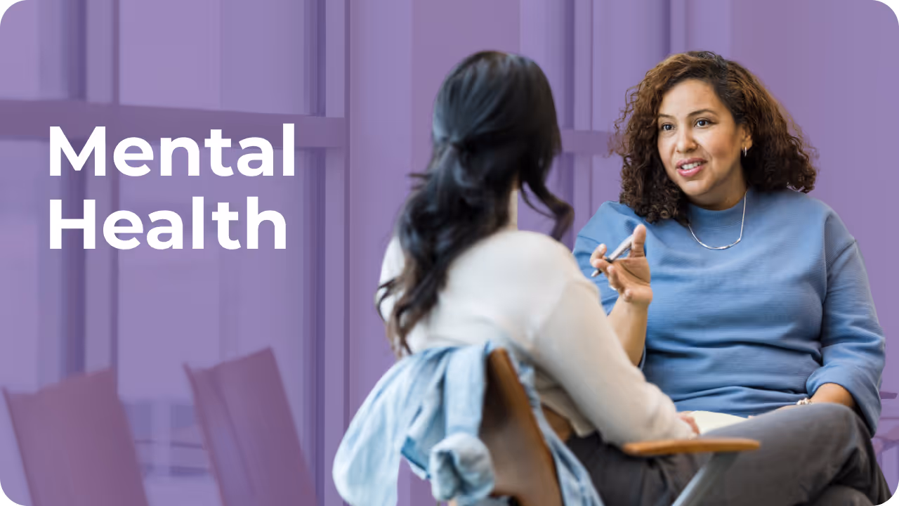 Two women are sitting and engaged in a conversation against a purple background with "Mental Health" text. The scene conveys support and empathy.