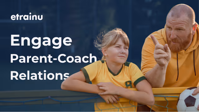 Young girl in yellow sports jersey leaning on a fence beside a man pointing and holding a soccer ball.