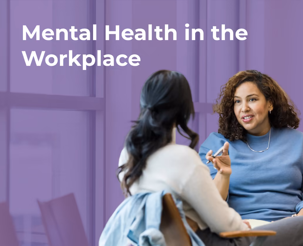 Two women having a discussion in an office setting about mental health in the workplace.