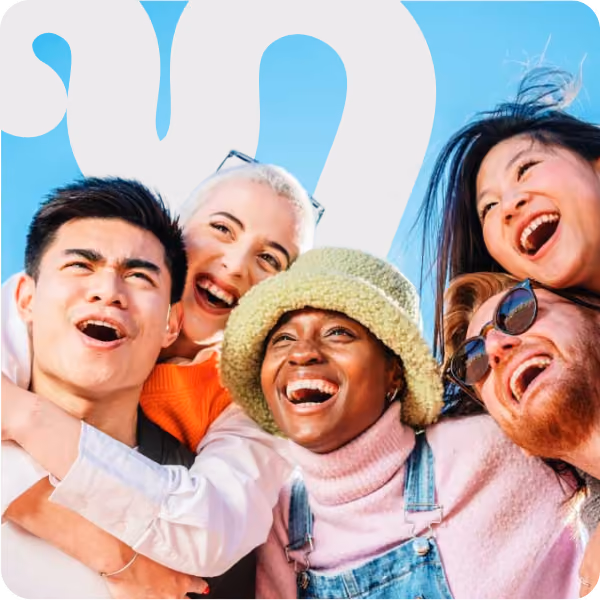 Group of five diverse friends smiling and laughing together under clear blue sky.