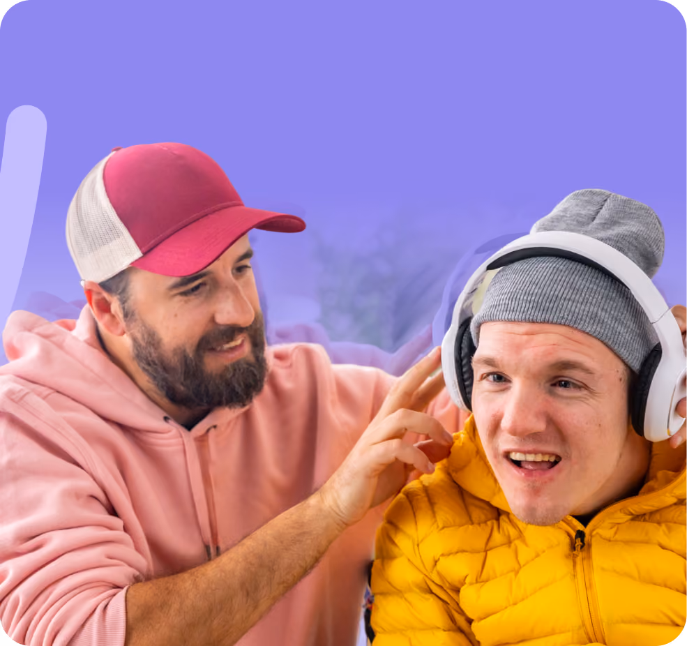 Man who is a support worker in a pink hoodie assisting his participant with putting on headphones