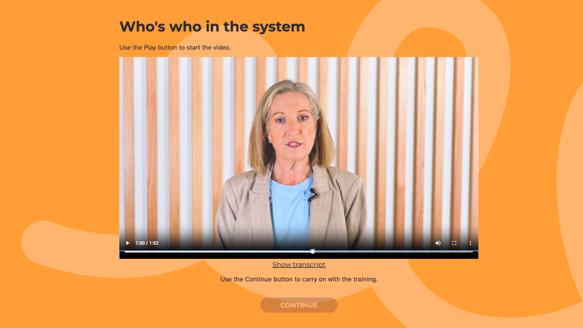 A presenter speaks to camera against a timber slat wall.